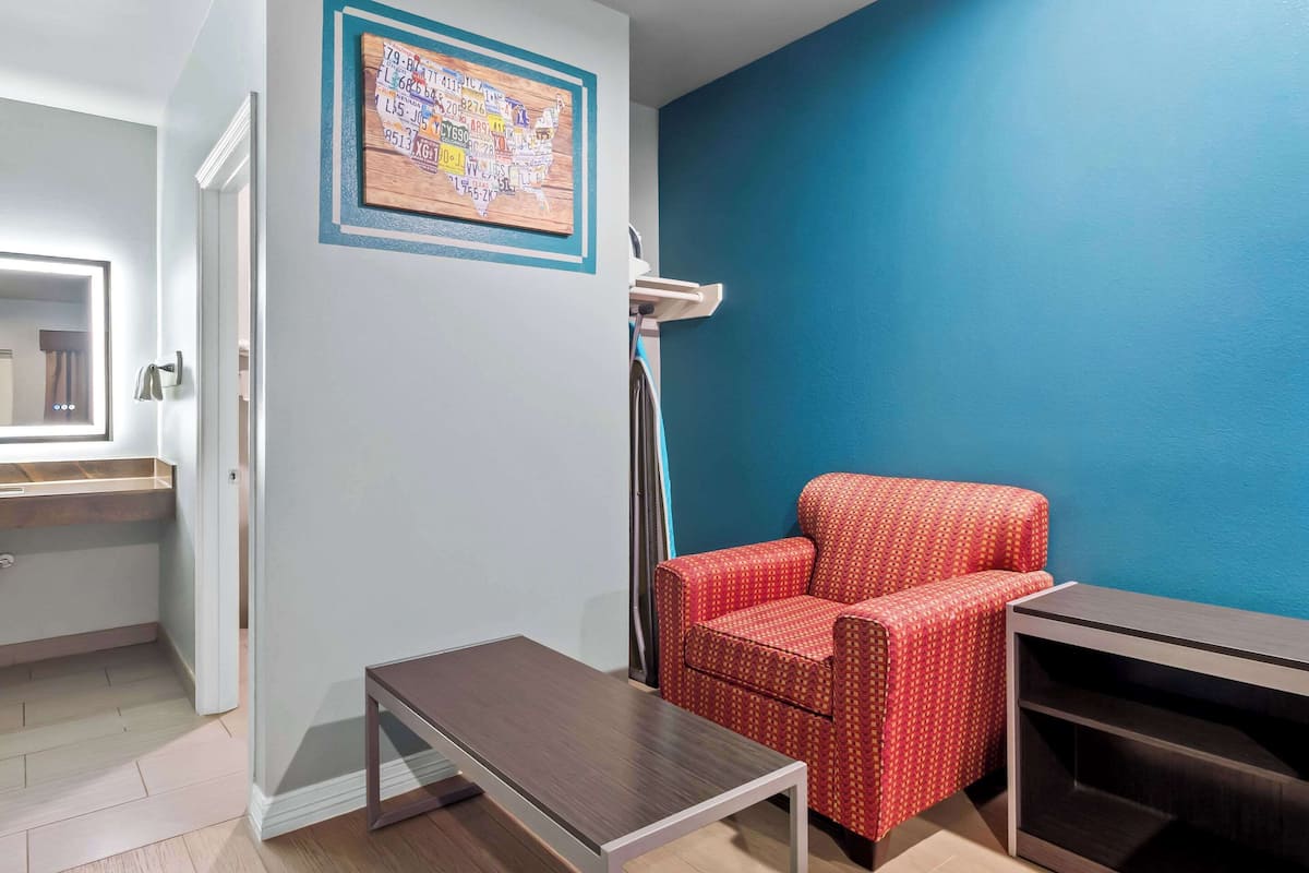 A room with a blue wall, a red patterned chair, a small table, and a map on the wall.