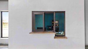 Un intérieur minimaliste avec une grande fenêtre, une petite étagère et un espace bureau.