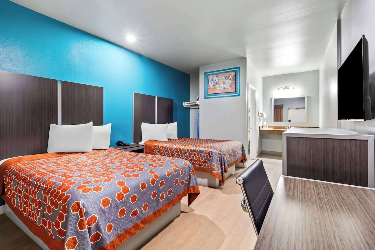 A hotel room with two beds, a desk, and a large mirror.