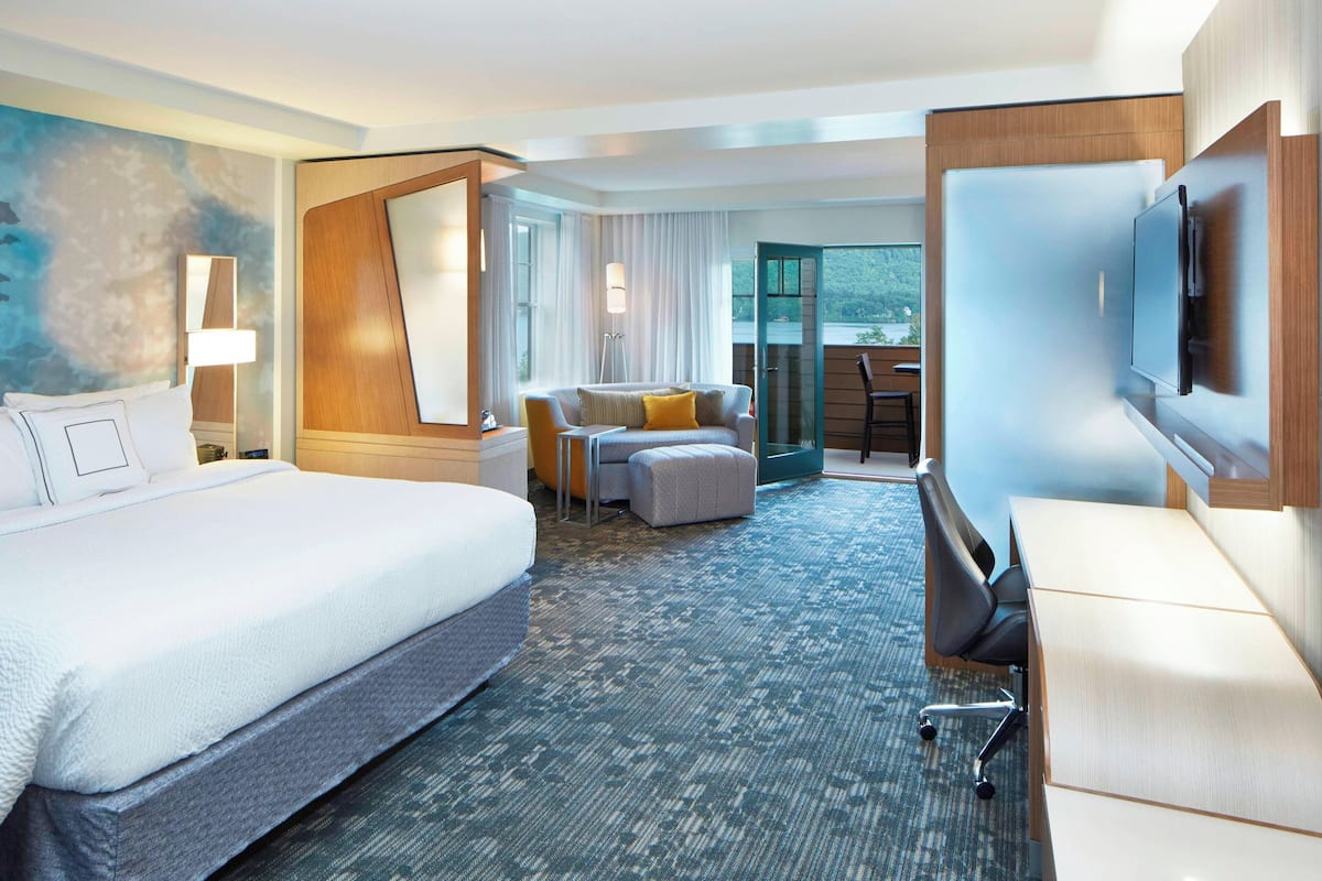 A hotel room with a large bed, a desk, a chair, and a television.