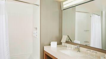 A modern bathroom with a shower, a sink, a mirror, and a towel rack.