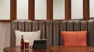 A seating area with a wooden table and chairs, a laptop, and a bottle of beer.