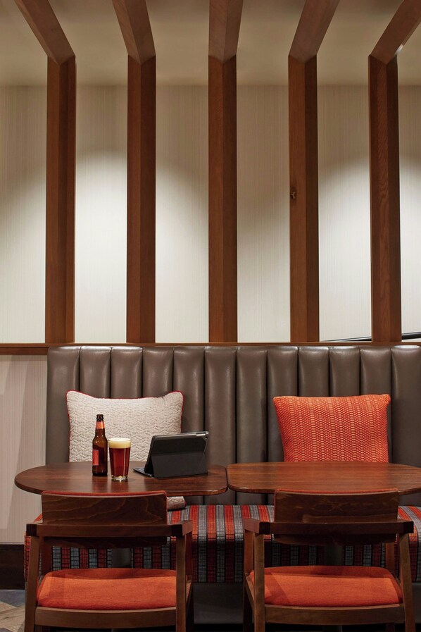 Una zona de estar con una mesa y sillas de madera, una computadora portátil y una botella de cerveza.