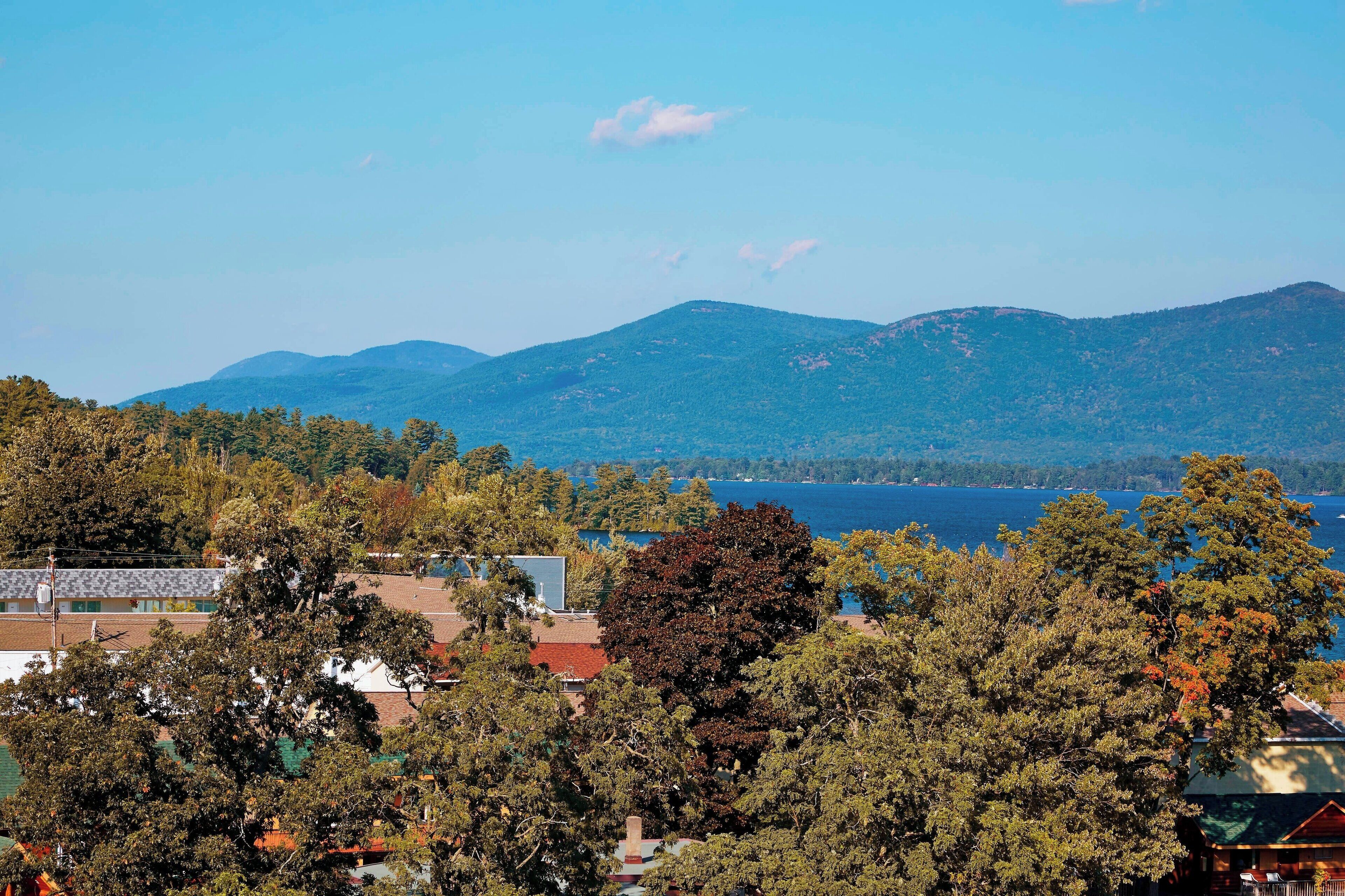 A view of a mountainous landscape with a lake in the background and trees in the foreground.