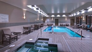 Zona de piscina interior con sillas de descanso y vestuario.