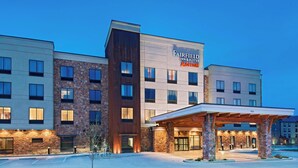 Un hotel Fairfield Inn & Suites by Marriott de varios pisos con un diseño moderno, que presenta una entrada cubierta y un césped bien cuidado.