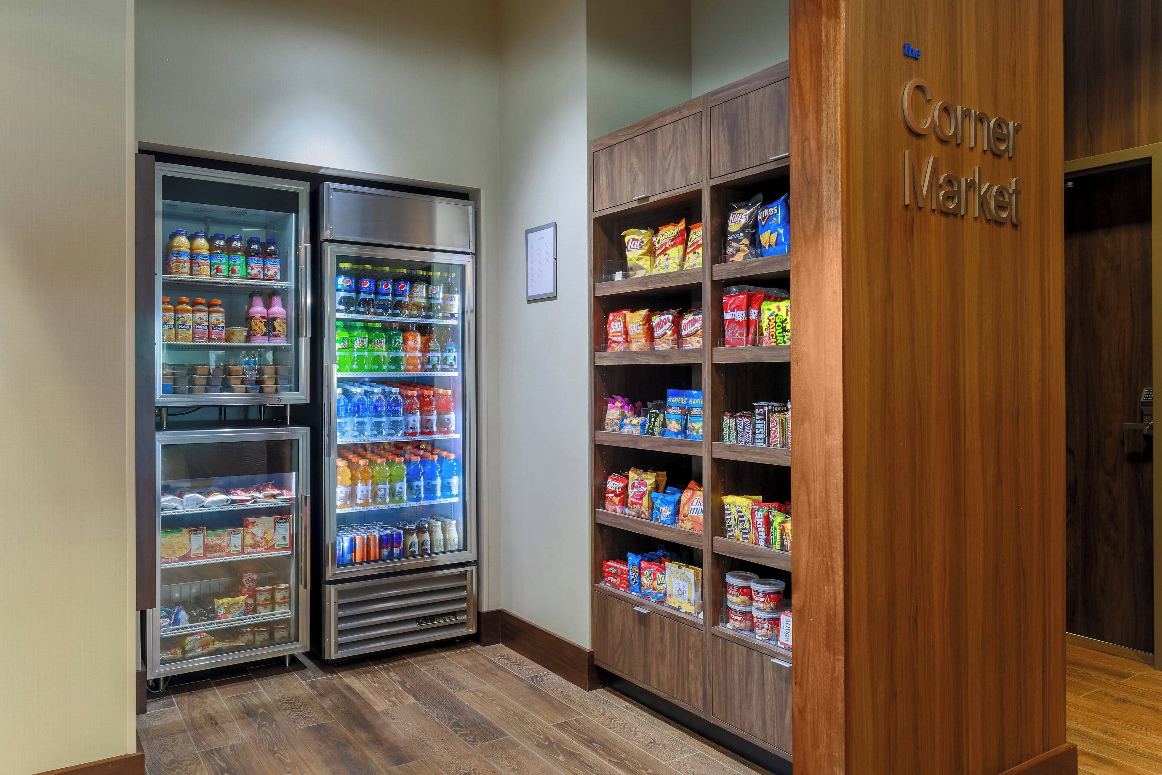A corner market with refrigerated beverage dispensers and shelves stocked with snacks and beverages.
