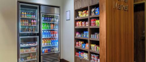 A corner market with refrigerated beverage dispensers and shelves stocked with snacks and beverages.