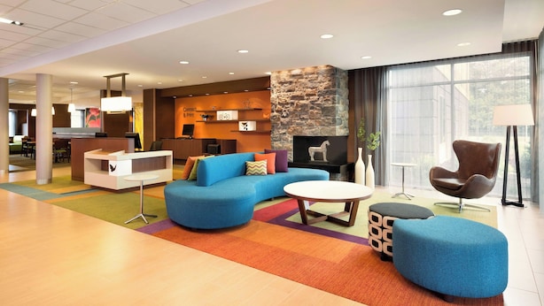 A spacious lobby with a blue sofa, a round coffee table, and a stone accent wall. - Fairfield Inn & Suites Lancaster East at The Outlets (Lancaster)