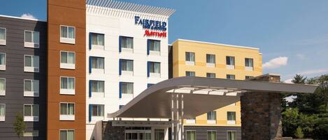 Een meerhoog Fairfield Inn & Suites by Marriott hotel met een modern ontwerp, met een overdekte ingang en een parkeerplaats.