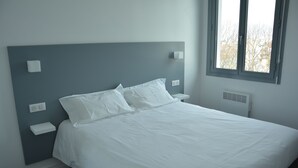 A bedroom with a bed, bedside tables, and a window. - Le Matisse (Pau)