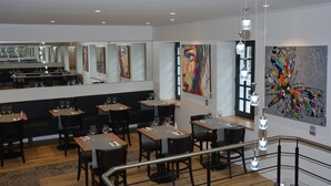 A modern restaurant with multiple dining tables and chairs, a bar area, and contemporary artwork on the walls. - Le Matisse (Pau)