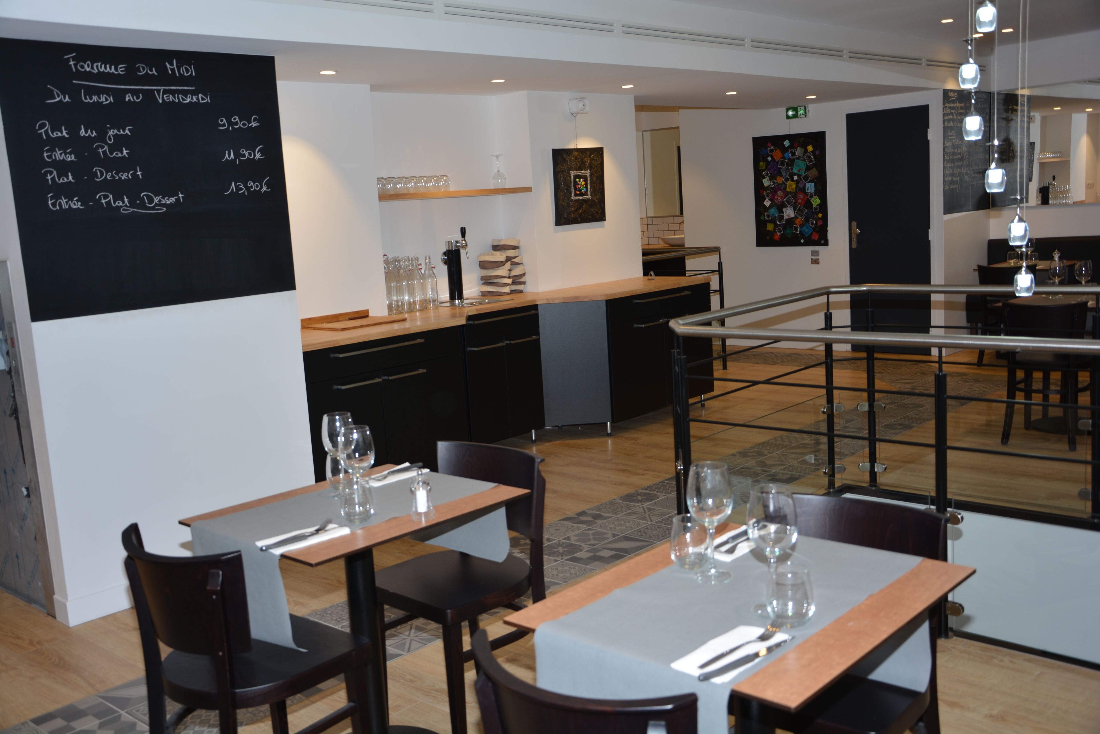 A restaurant with a chalkboard menu listing daily specials, wooden tables with chairs, and a modern interior design.