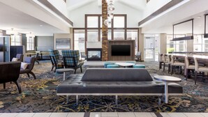 A spacious lobby with a high ceiling, a fireplace, and a mix of seating areas including sofas and chairs.
