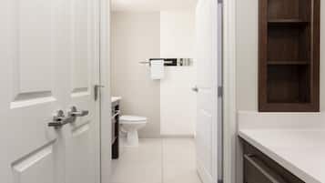 Un baño moderno con un inodoro, un perchero para toallas y un armario de madera.