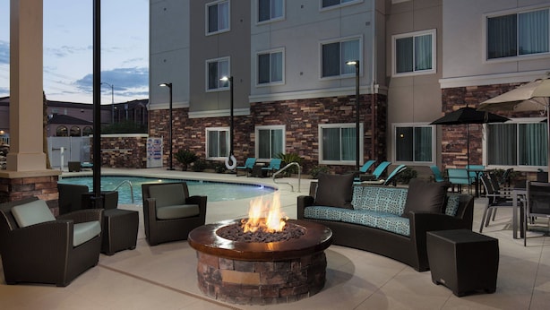 A poolside area with a fire pit, outdoor seating, and a pool.