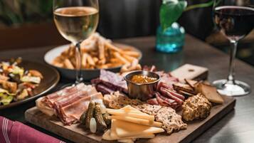 A charcuterie board with various meats, cheeses, and pickles, accompanied by glasses of wine.