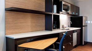A modern kitchen with a wooden countertop, a sink, a microwave, and a refrigerator.