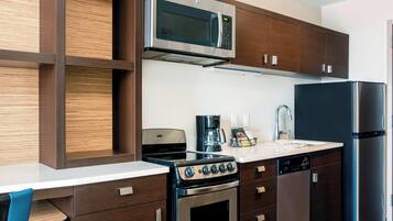 A modern kitchen with a built-in microwave, stove, and dishwasher, featuring wooden cabinetry and a white countertop.