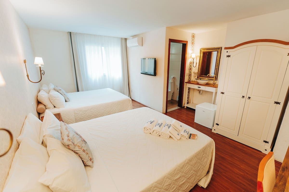 A hotel room with two beds, a bathroom, and a wardrobe.