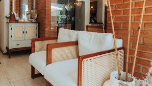 Un salon avec un canapé, une table basse, un miroir et un mur en briques.