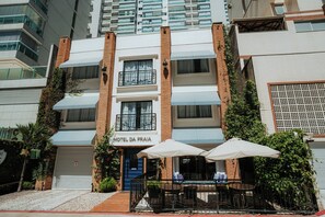 A hotel with a blue door, outdoor seating with umbrellas, and a sign reading 'HOTEL DA PRAIA'. - Hotel da Praia (Vila Velha)