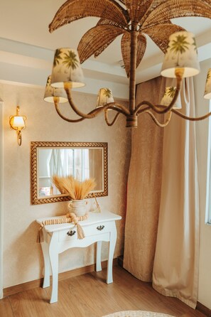 A room with a white console table, a mirror, a wicker chandelier, and a beige curtain. - Hotel da Praia (Vila Velha)