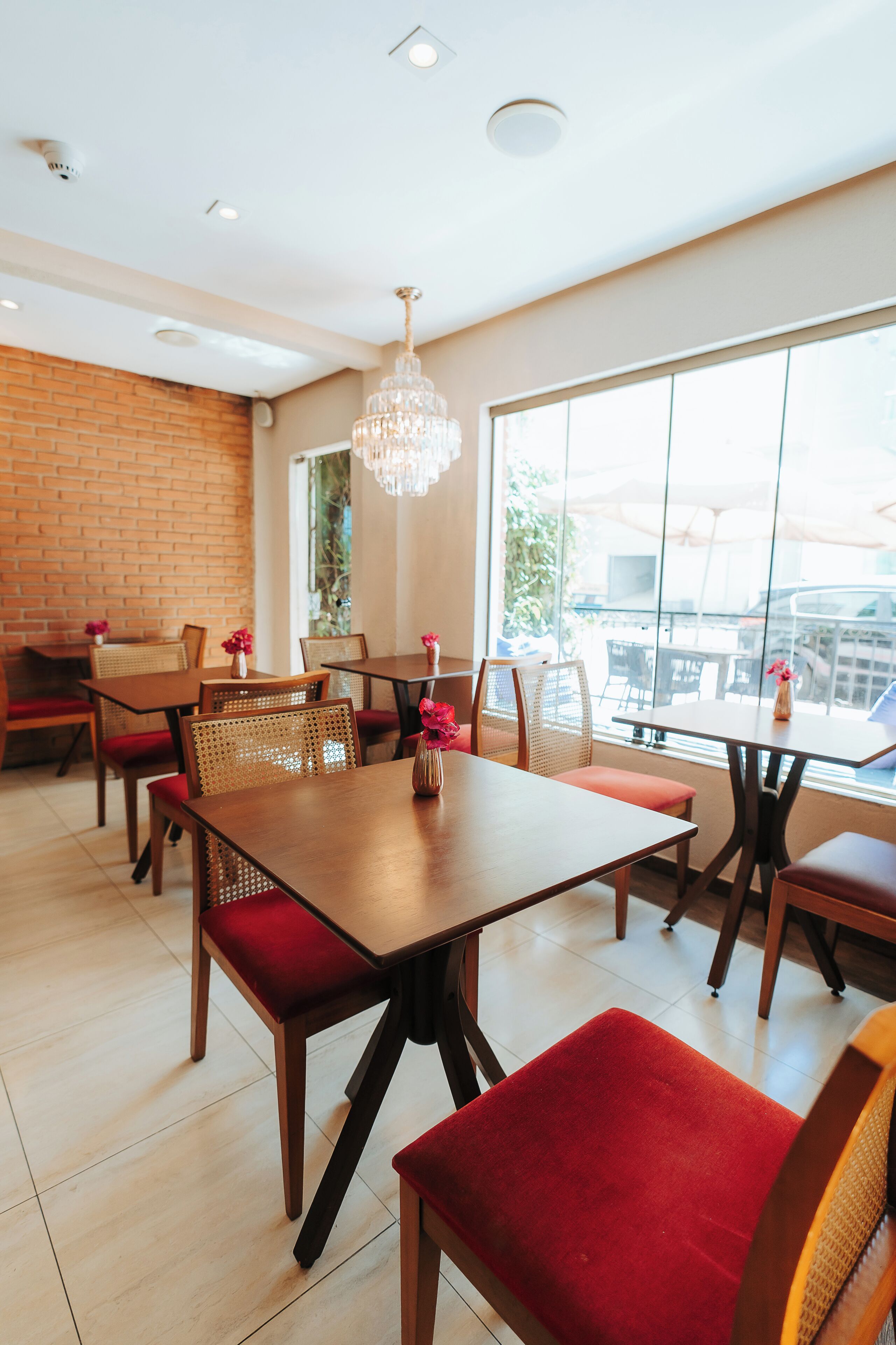 Un restaurant avec des tables et des chaises en bois, un mur en briques et une grande fenêtre donnant sur un beau paysage.
