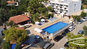 Un hotel con piscina, sillas de descanso y aparcamiento.