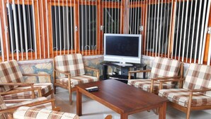 Una sala de estar con una mesa de centro de madera, sillones a cuadros, un televisor y un control remoto.