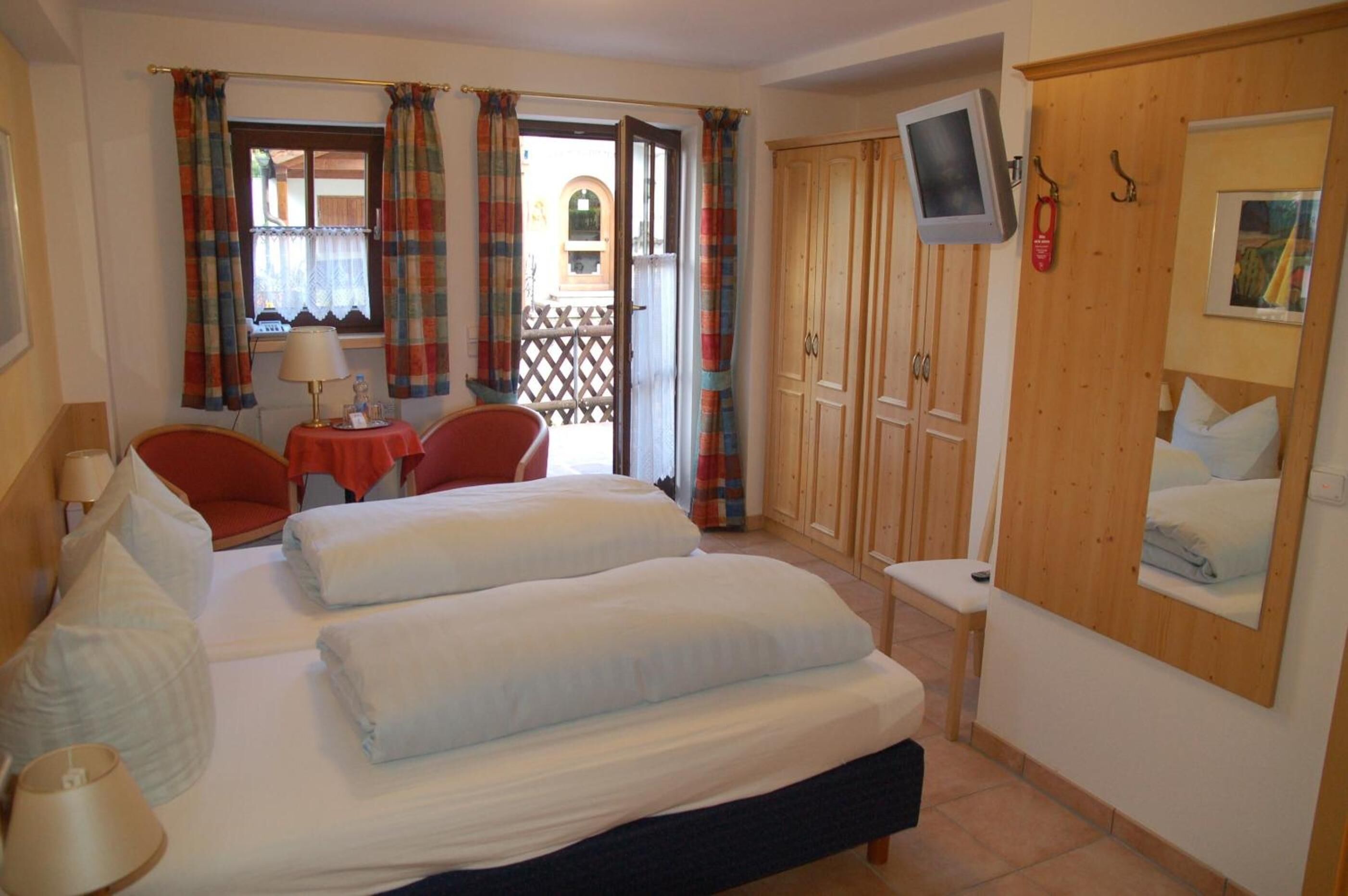 Una habitación de hotel con una cama, un escritorio, una silla, un televisor y un armario.