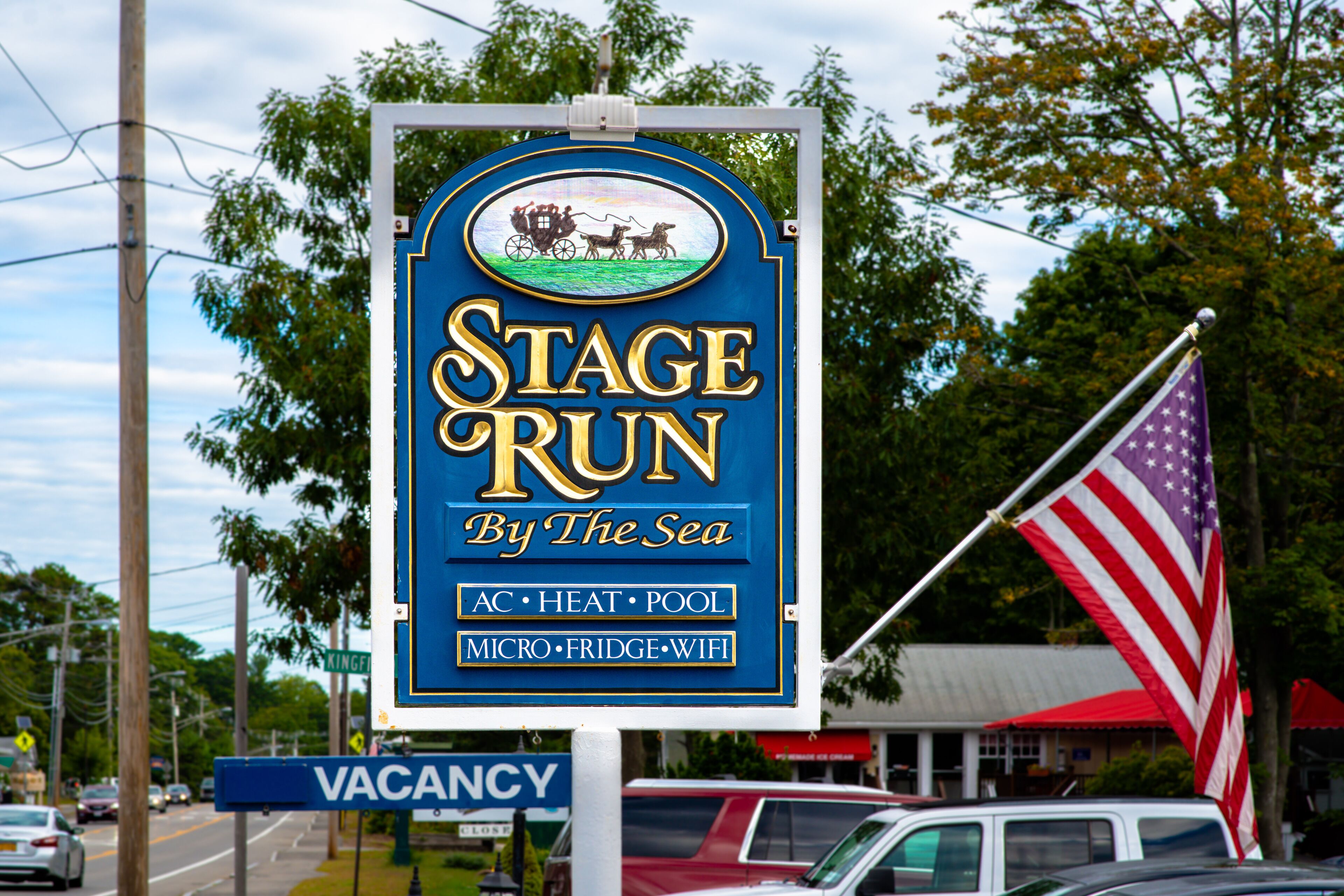 Une pancarte indiquant « Stage Run By The Sea » et énumérant les équipements disponibles, tels que la climatisation, le chauffage, une piscine, un mini-réfrigérateur et une connexion Wi-Fi.