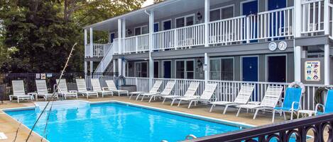 A pool area with lounge chairs and a staircase leading to a balcony.