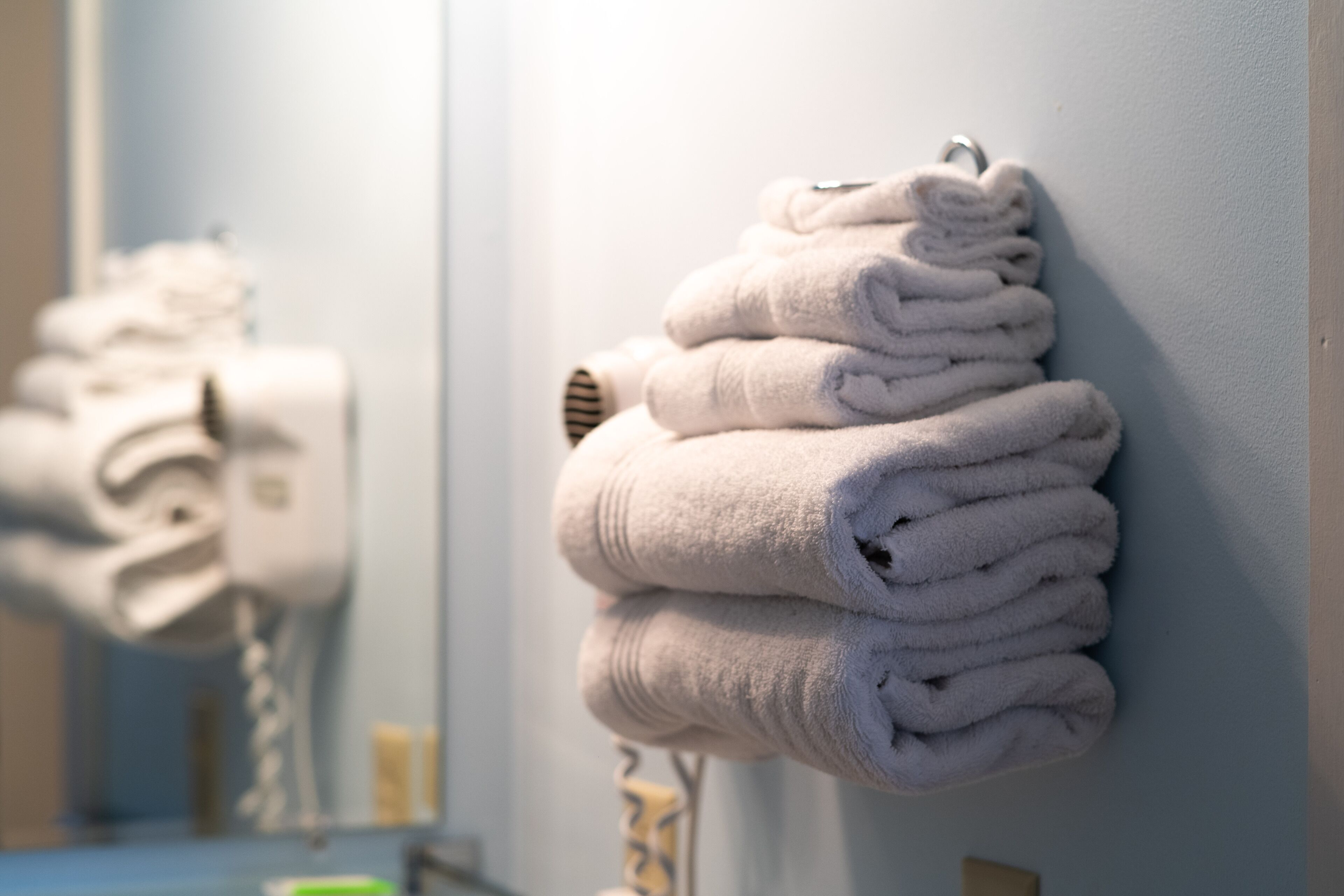A stack of folded towels on a wall near a mirror.