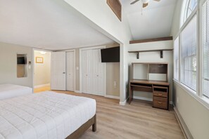 A bedroom with a bed, a desk, a TV, and a walk-in closet.
