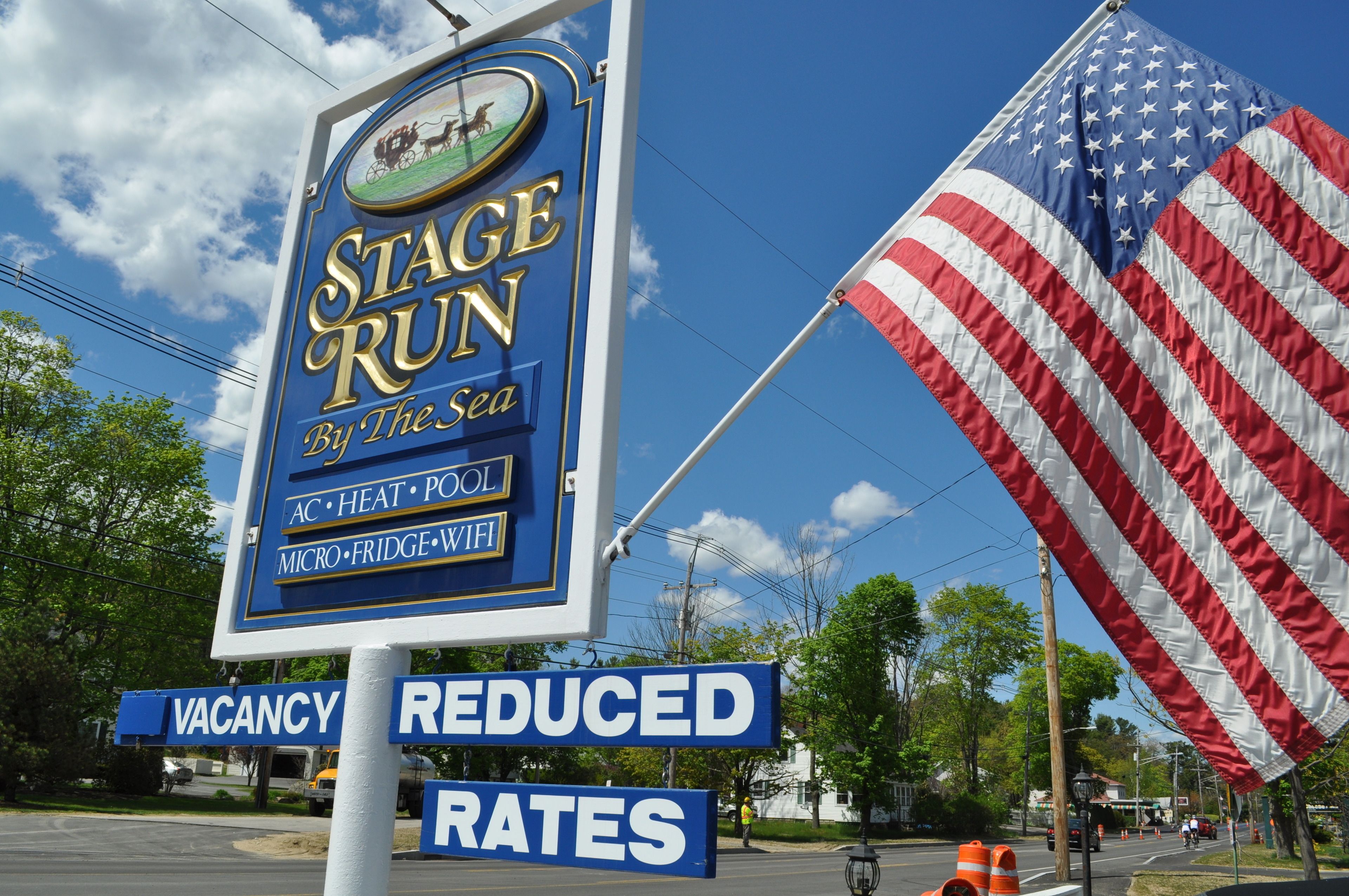 A sign for a hotel named "Stage Run By The Sea" with amenities including AC, heat, pool, and WiFi.