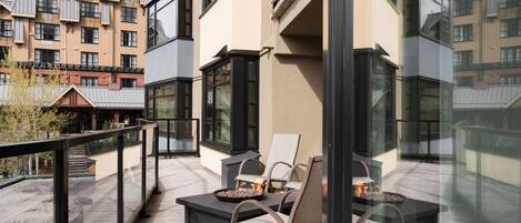 A balcony with outdoor seating and a fire pit.