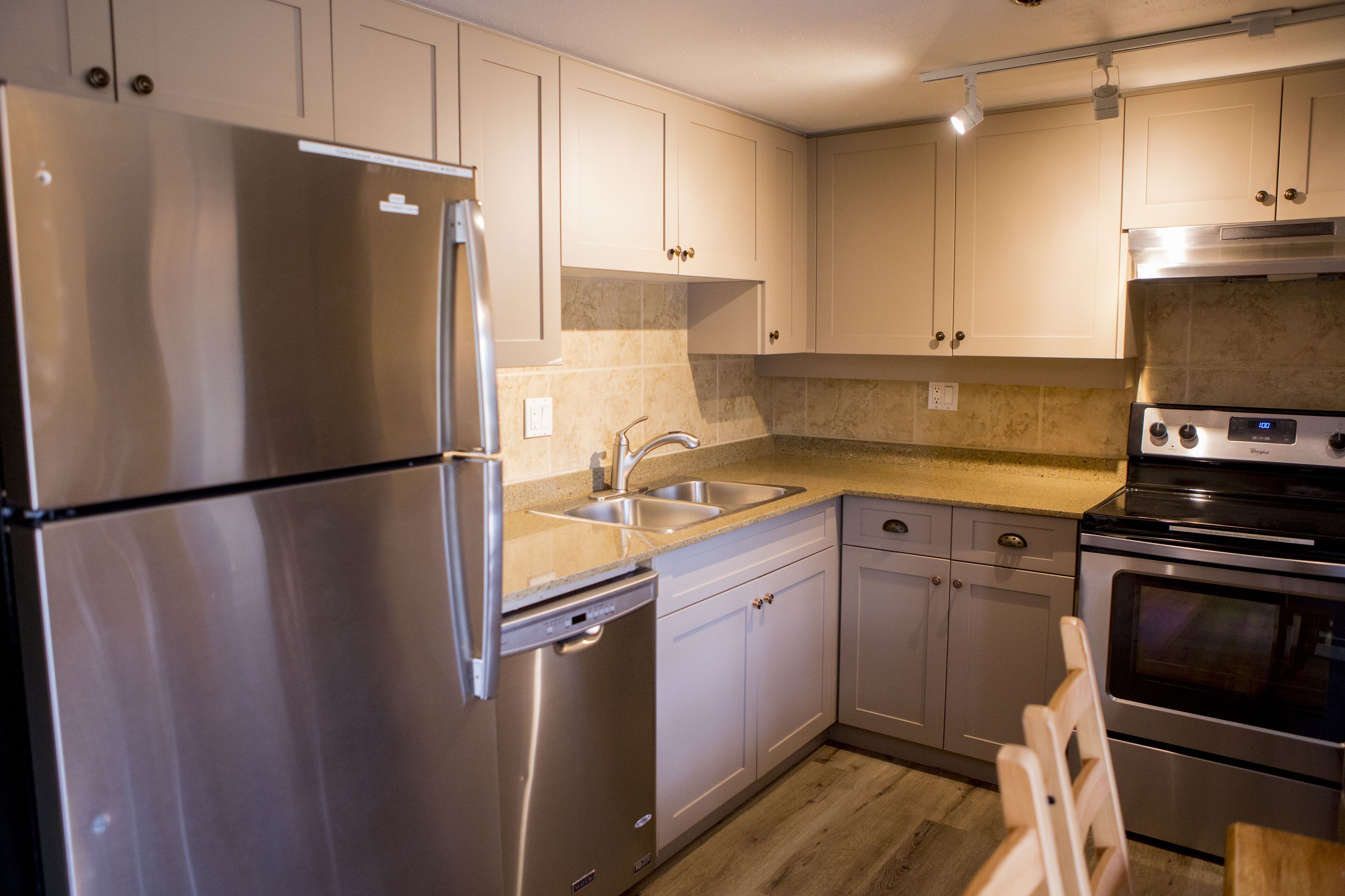A modern kitchen with stainless steel appliances, a double sink, and light-colored cabinetry.