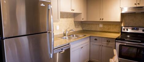 A modern kitchen with stainless steel appliances, a double sink, and light-colored cabinetry.