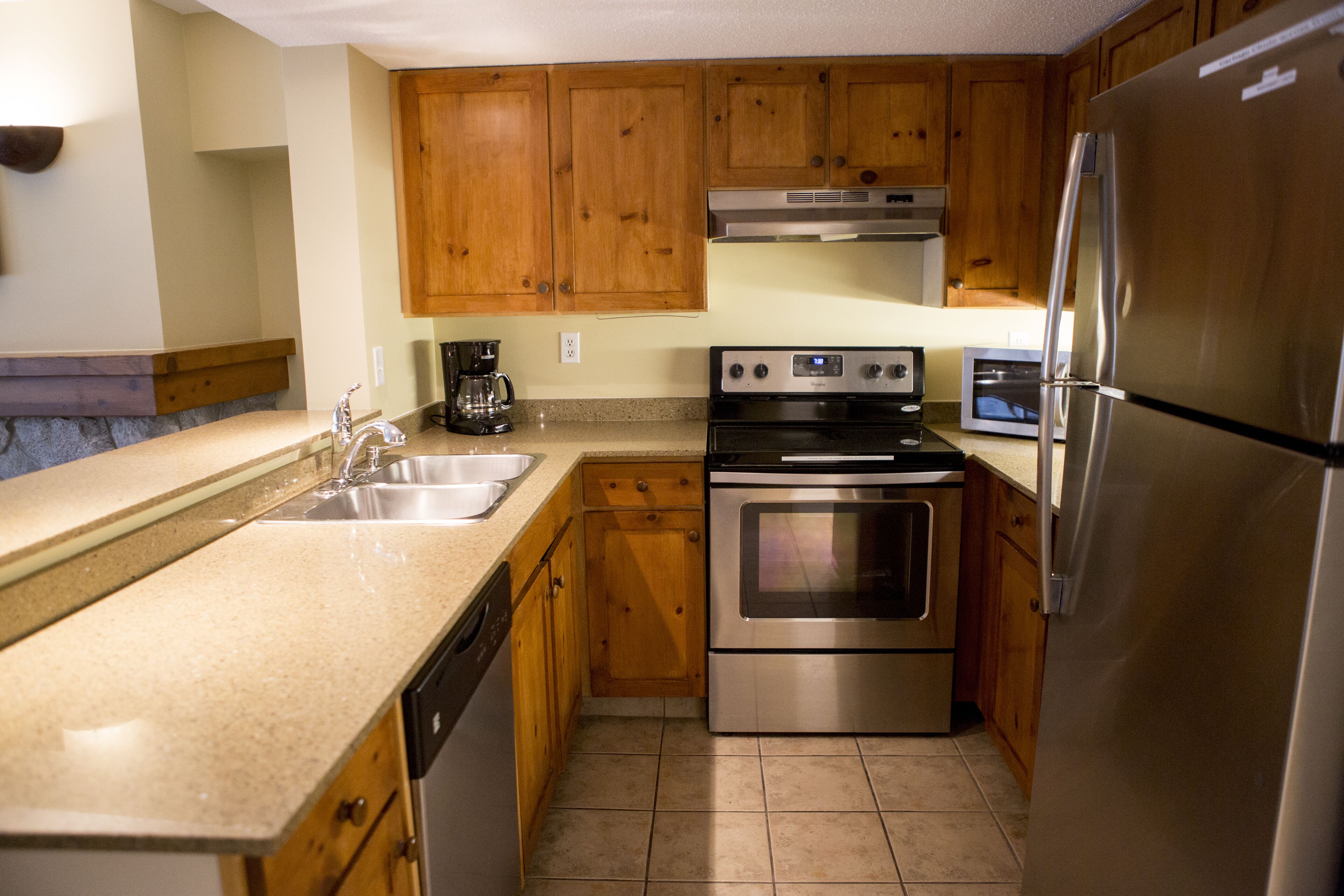 A kitchen with wooden cabinets, stainless steel appliances, a dishwasher, and a coffee maker.