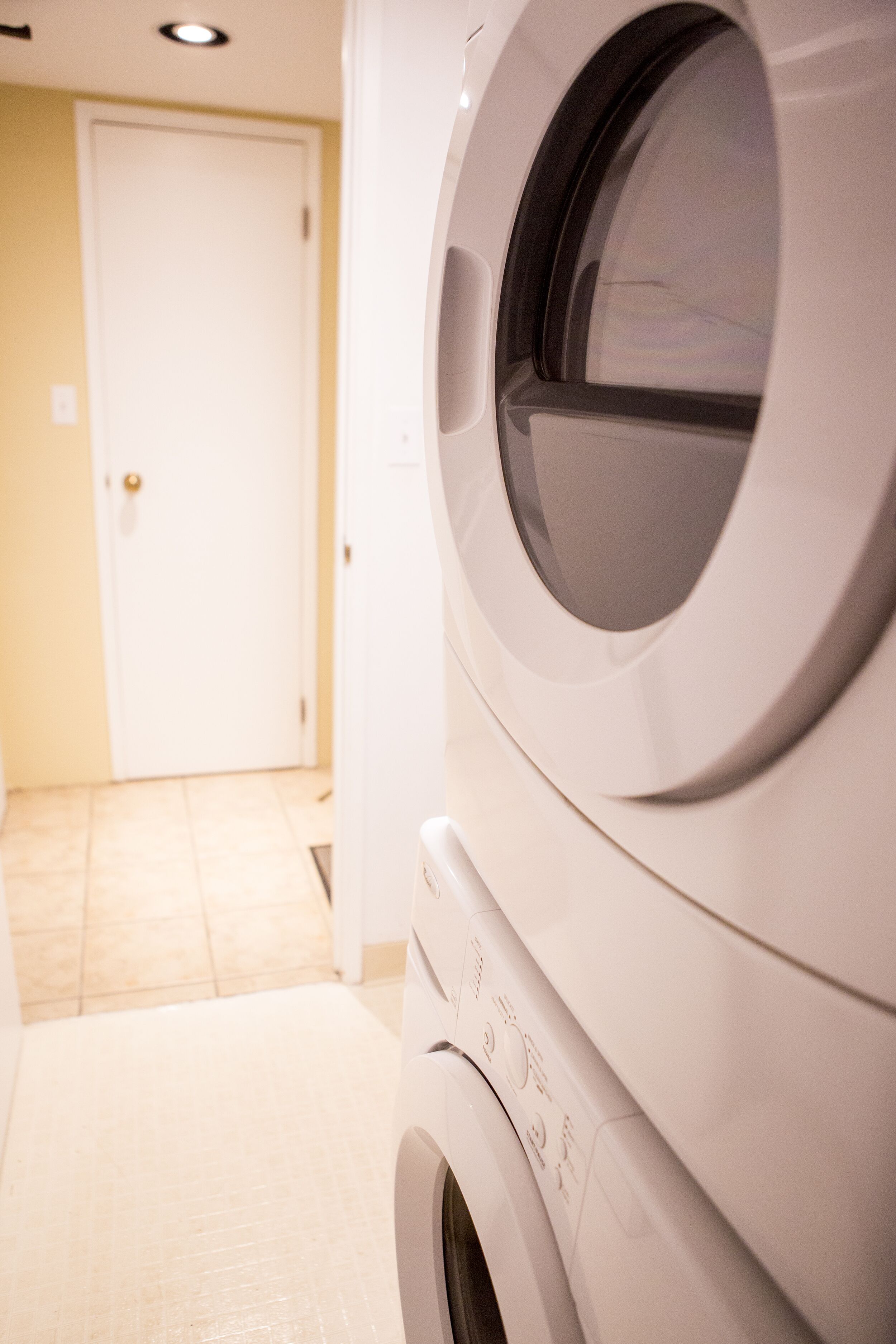 A front view of a washing machine in a laundry room with a door in the background.