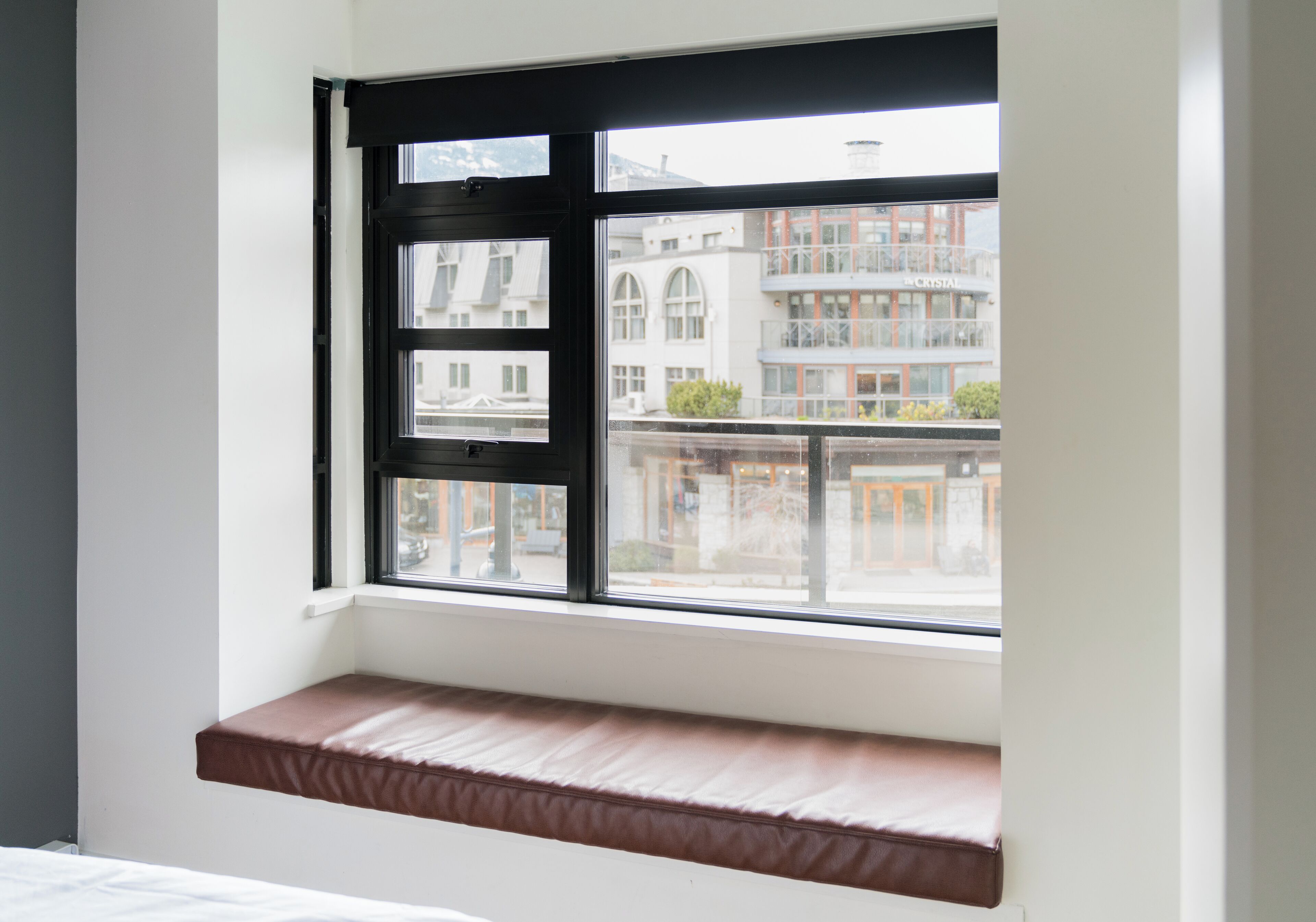 A room with a window seat and a view of buildings outside.