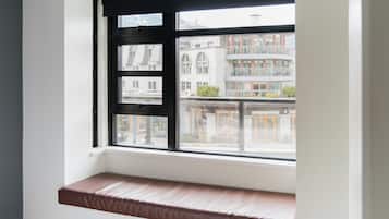 A room with a window seat and a view of buildings outside.