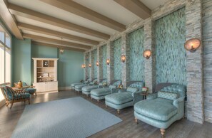 A room with a stone wall, a wooden cabinet, and multiple upholstered chairs.