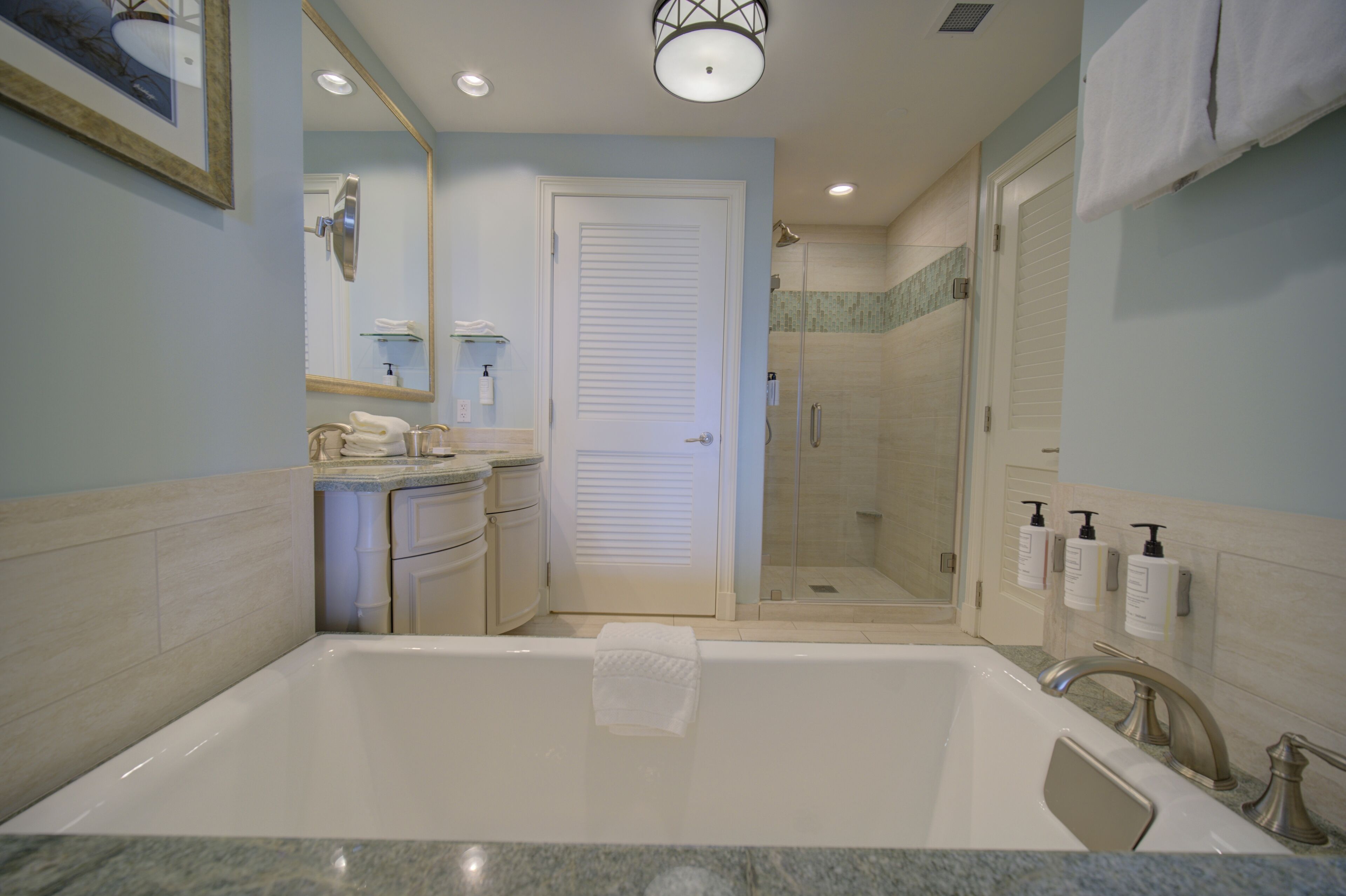 A modern bathroom with a large bathtub, a shower area, and a vanity with a mirror.
