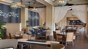 A spacious dining area with high ceilings, ceiling fans, and decorative lighting.