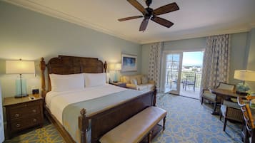 A hotel room with a large bed, a bench, a dining table, and a balcony with a view.