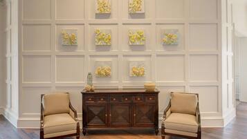 A room with a wooden cabinet, two armchairs, and a wall with framed artwork.
