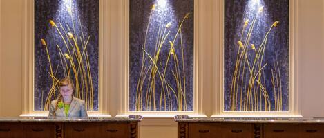 A person standing in front of a counter with three framed artworks depicting tall grasses.
