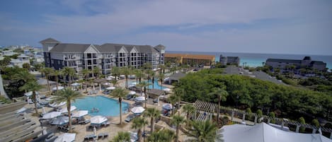 A resort with a large pool, multiple buildings, and a view of the ocean.